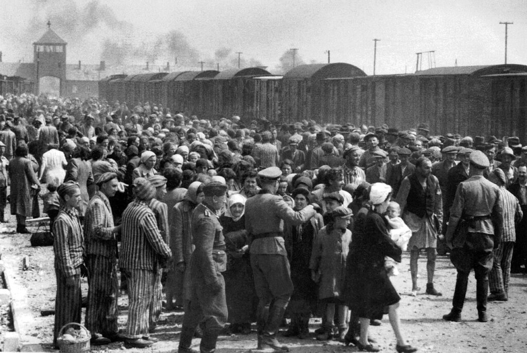 By Bernhard Walter - Yad Vashem: "Jews undergoing selection on the ramp. Visible in the background is the famous entrance to the camp. Some veteran inmates are helping the new comers.", Public Domain, https://commons.wikimedia.org/w/index.php?curid=39226962